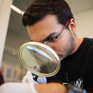 A student examines a document with a magnifying glass.