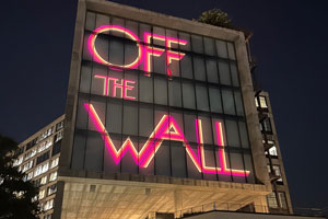 words 'off the wall' projected in bright colors on the side of a building